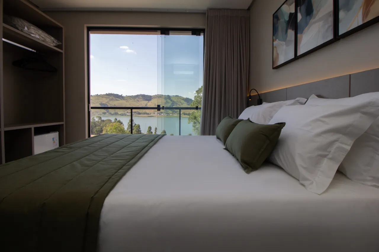 Bed in the Master Suite at Bellville Pousada, with the lake view through the window