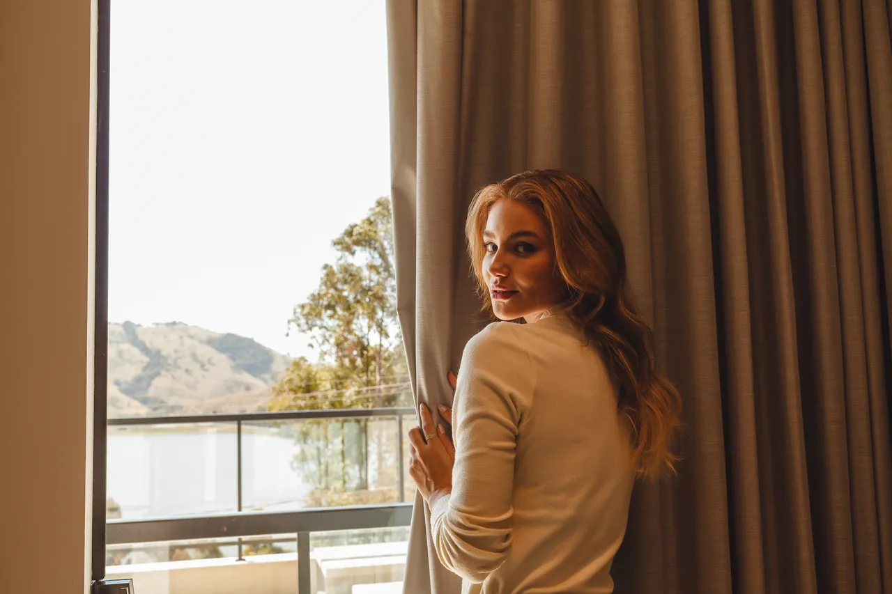 Guest opening the curtain of the Master Suite, with the lake in the background