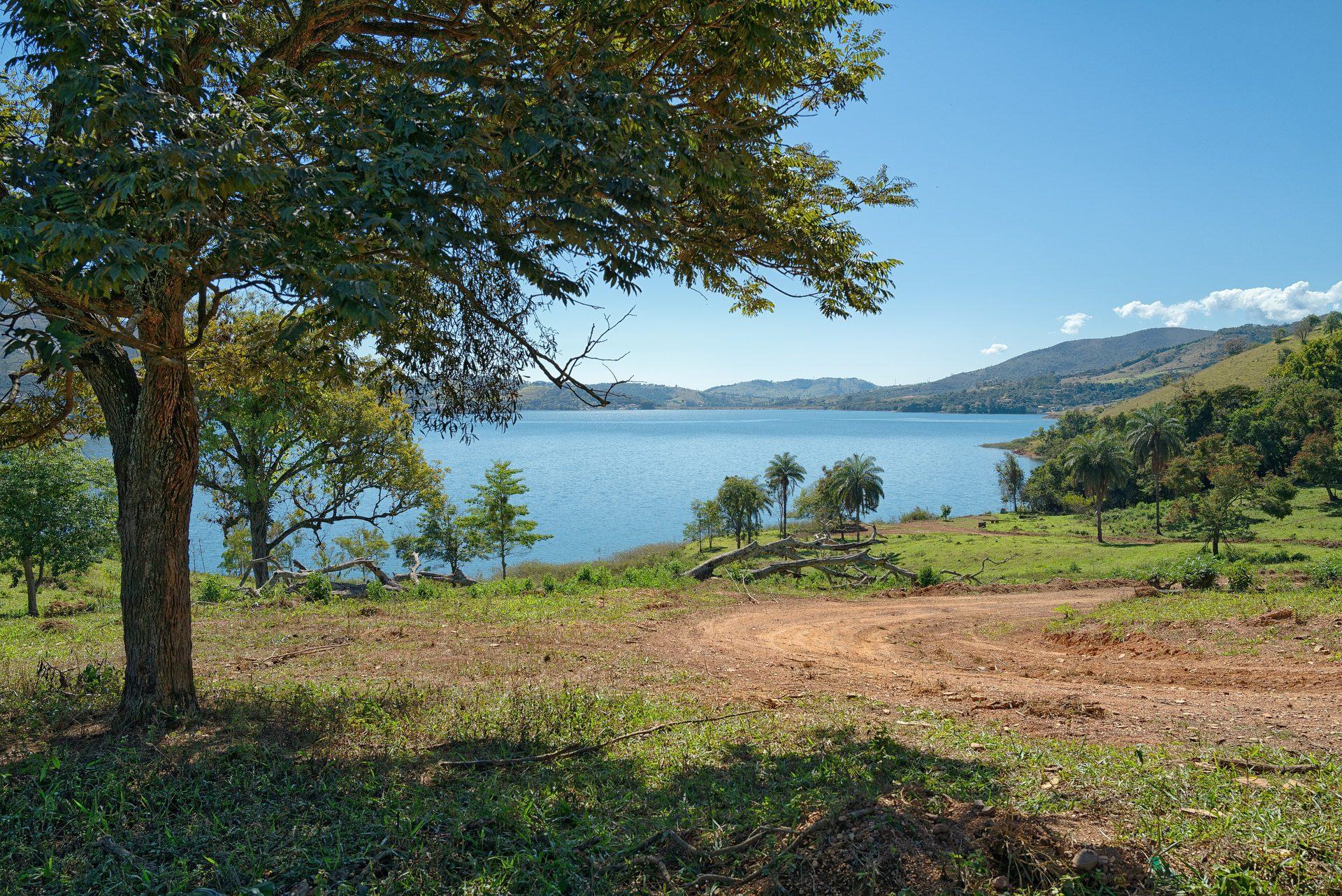 Camino de tierra que lleva al Lago de Furnas, entre árboles y pastizal, en Capitólio
